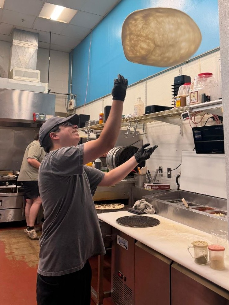Picture of me tossing a pizza in the kitchen I work at with the dough in midair